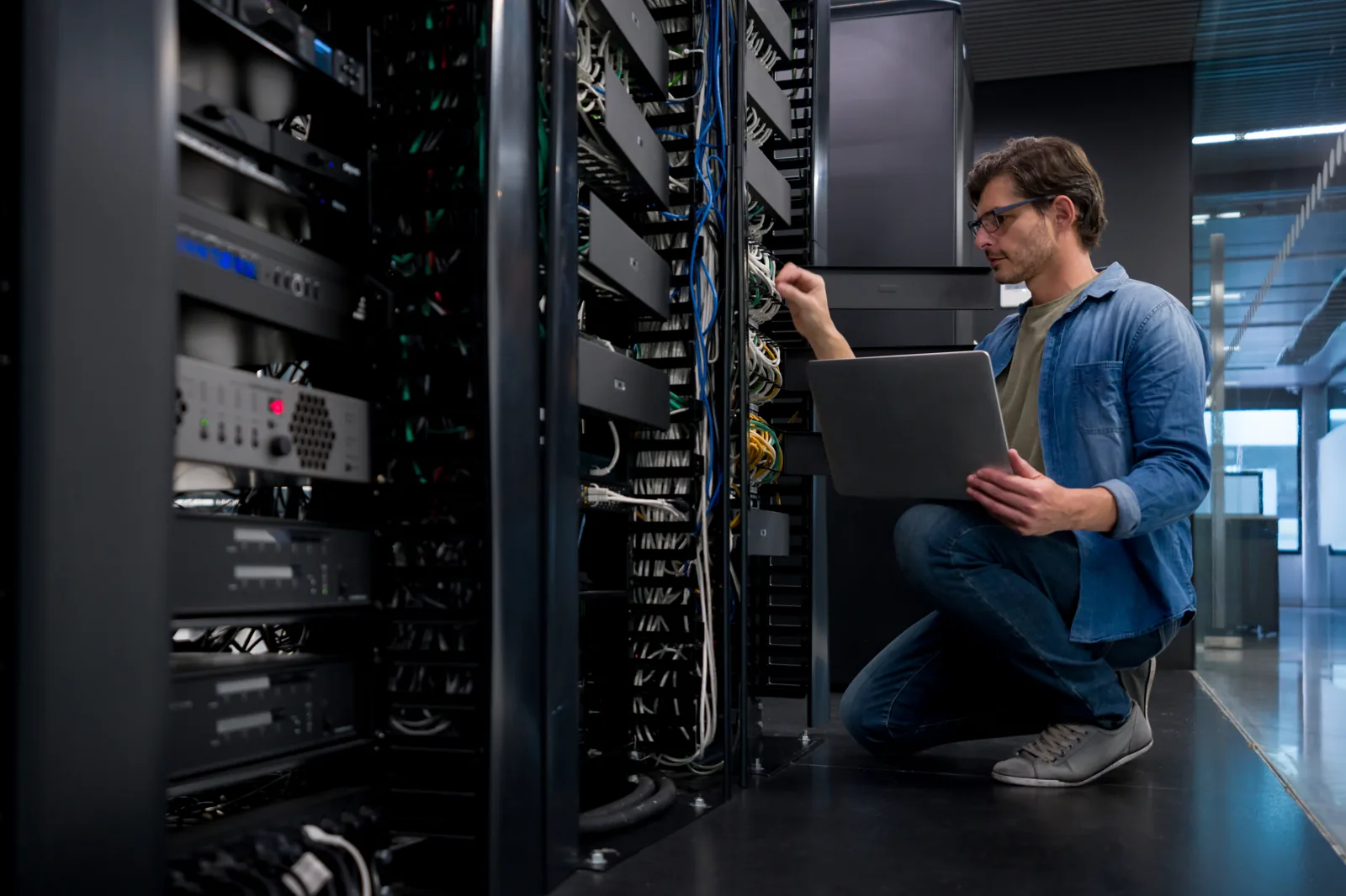 QuantVPS engineer working on connections at an open server rack